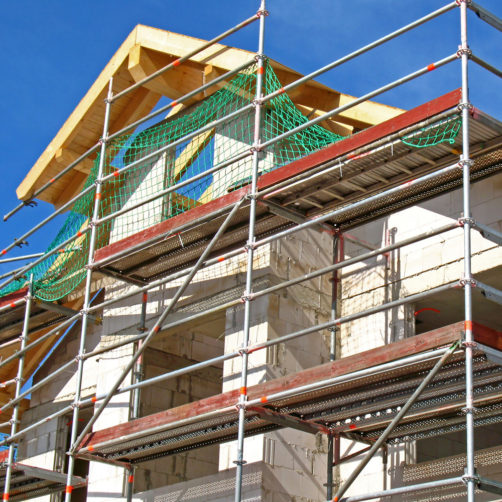 Eingerüstete Hausfassade mit neuem Vollwärmeschutz unter blauem Himmel